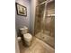 Cozy bathroom features a glass-enclosed shower, toilet, and neutral tile flooring at 8973 Cat Palm Rd, Kissimmee, FL 34747