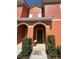 Inviting front door with arched entryway, bench and well-manicured shrubs at this two story home at 8973 Cat Palm Rd, Kissimmee, FL 34747