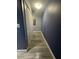 Hallway with light gray floors and blue accent walls that lead to closet and electrical access at 8973 Cat Palm Rd, Kissimmee, FL 34747