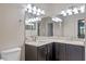 Bathroom with dual sinks, dark cabinets, granite counters, and large mirror at 1017 Green Gate Blvd, Groveland, FL 34736