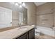 Well-lit bathroom featuring granite counters, a dark vanity, ceramic tile flooring, and a tub with tile surround at 1017 Green Gate Blvd, Groveland, FL 34736