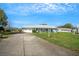 Charming single-story home with an attached garage and a long driveway, set against a blue sky at 1033 Scotch Pine Ct, Leesburg, FL 34788