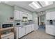 Bright kitchen with white cabinets, tile floors, and stainless steel microwave on wood cart at 1033 Scotch Pine Ct, Leesburg, FL 34788