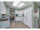 Bright kitchen with white appliances and cabinets, tile flooring, and view into dining room at 1033 Scotch Pine Ct, Leesburg, FL 34788