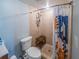 Compact bathroom showcasing a toilet, tiled shower with a curtain, and storage, designed for efficient use of space at 1051 S Highland St # 7E, Mount Dora, FL 32757