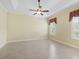 Spacious bedroom with tile floors, fan and tray ceiling, and a window with decorative valance at 10929 Se 167Th Pl, Summerfield, FL 34491