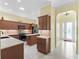 A spacious kitchen with stone countertops, stainless steel appliances, wooden cabinets, and ceramic tile flooring at 10929 Se 167Th Pl, Summerfield, FL 34491