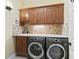 The laundry room features wood cabinets, stone backsplash, and modern washer and dryer at 10929 Se 167Th Pl, Summerfield, FL 34491