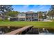 Back of home overlooking waterfront featuring a private dock, screened patio, and lush green lawn at 11007 Lake Katherine Cir, Clermont, FL 34711