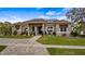 Attractive single-story home boasting a brick driveway, manicured lawn, mature plantings, and sunshades over windows at 11007 Lake Katherine Cir, Clermont, FL 34711