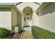 Inviting front entrance with an arched doorway, a decorative wreath, and a well-maintained walkway and landscape at 11684 Sw 72Nd Cir, Ocala, FL 34476