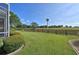 Spacious green backyard with a wooden fence and peaceful views of surrounding trees and landscape at 1229 Augustine Dr, The Villages, FL 32159