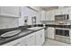 Galley-style kitchen features stainless steel appliances, white cabinets, and a black countertop at 1229 Augustine Dr, The Villages, FL 32159