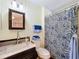 Bathroom with dark vanity, marbled countertop, updated fixtures, decorative mirror and blue paisley shower curtain at 1340 Elkhart Cir, Tavares, FL 32778