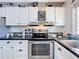 Cozy kitchen featuring white cabinetry, black countertops, and stainless steel appliances at 1340 Elkhart Cir, Tavares, FL 32778