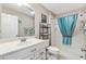 Bright bathroom with a single sink vanity, large mirror, shower with a blue curtain, and tiled floors at 1380 Mayesville Way, The Villages, FL 32162