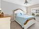 Comfortable bedroom with a white and wood trimmed bed, two nightstands, and bright window at 1380 Mayesville Way, The Villages, FL 32162