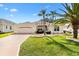 Charming single-story home with an attached garage, manicured lawn, and beautiful palm tree landscaping at 1380 Mayesville Way, The Villages, FL 32162