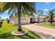 Charming single-story home with an attached garage, manicured lawn, and beautiful palm tree landscaping at 1380 Mayesville Way, The Villages, FL 32162