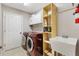 Well-equipped laundry room with red washer and dryer, utility sink, white cabinets, and a fire extinguisher at 1380 Mayesville Way, The Villages, FL 32162