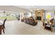Open-concept living room featuring a stone fireplace, tile flooring, and golf course views at 1380 Mayesville Way, The Villages, FL 32162