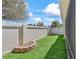 Grassy backyard with a tall wall and a small stone garden on the side at 1487 Gantt St, The Villages, FL 32162