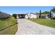Attractive home showcasing a manicured front lawn, long brick-paved driveway, and covered parking space at 1510 E Schwartz Blvd, The Villages, FL 32159