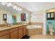 Well-lit bathroom featuring double sinks, a soaking tub, and a separate toilet room at 15475 Camp Dubois Cres, Winter Garden, FL 34787
