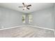 A spacious bedroom with two windows bringing in natural light and carpeted floors and a ceiling fan at 1638 Leesburg Blvd, Fruitland Park, FL 34731