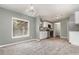 Open living space with white cabinets, stainless appliances, and an adjacent carpeted room at 1638 Leesburg Blvd, Fruitland Park, FL 34731