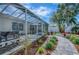 Enclosed patio with outdoor kitchen, seating, lush landscaping, and paved walkway at 17714 Se 84Th Sheldon Ter, The Villages, FL 32162