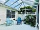 Relaxing patio featuring comfortable Adirondack chairs, lush greenery, and a screened enclosure at 17714 Se 84Th Sheldon Ter, The Villages, FL 32162