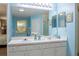 Double vanity bathroom with large mirror, white cabinets, and light blue walls at 1792 Presidio Dr, Clermont, FL 34711