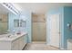 Bathroom with double vanity, glass-enclosed shower, and light blue walls at 1792 Presidio Dr, Clermont, FL 34711