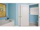This bathroom has an interior door and tub with blue walls and decorative artwork at 1792 Presidio Dr, Clermont, FL 34711