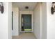 Inviting front door with decorative glass, flanked by sconce lighting and lush landscaping at 1792 Presidio Dr, Clermont, FL 34711