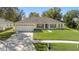 Single-story home featuring a spacious lawn, a two-car garage, mature trees, and welcoming front porch at 1792 Presidio Dr, Clermont, FL 34711