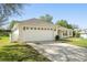 A two-car garage with carriage doors is complemented by a well-maintained driveway and manicured front lawn at 1792 Presidio Dr, Clermont, FL 34711