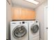 A laundry room with a washer and dryer set, overhead cabinets and a door at 181 Sutter Dr, Clermont, FL 34711