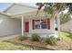Close-up of a charming covered front porch with a red door and decorative rock landscaping at 2082 Harston Trl, The Villages, FL 32162