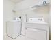 Functional laundry room features a washer, dryer, ironing board and storage shelf at 2116 Lelani Cir, Davenport, FL 33897