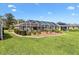 Expansive yard with a well-maintained lawn and manicured landscaping, leading to a screened-in lanai at 2126 Sansores St, The Villages, FL 32159