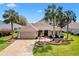 Beautiful tan home with well manicured lawn, decorative fountain, and mature palm trees at 2126 Sansores St, The Villages, FL 32159