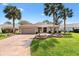 Beautiful tan home with well manicured lawn, decorative fountain, and mature palm trees at 2126 Sansores St, The Villages, FL 32159