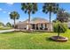Beautiful tan home with well manicured lawn, decorative fountain, and mature palm trees at 2126 Sansores St, The Villages, FL 32159