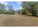 Backyard of a house with dead grass, a screened in porch, a fence, and lush trees at 21311 Sw Marine Blvd, Dunnellon, FL 34431