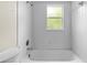 Bathroom showcases a shower-tub combo with white tiles and a window at 21311 Sw Marine Blvd, Dunnellon, FL 34431
