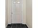 This white front door features windows and a brass knob and is flanked by neutral-toned walls at 21311 Sw Marine Blvd, Dunnellon, FL 34431