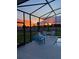 Screened-in pool area with patio furniture overlooking the lawn during an incredible sunset at 2174 Wallingford Loop, Mount Dora, FL 32757