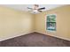 A cozy bedroom featuring neutral walls, carpet, a ceiling fan, and a window offering natural light at 2376 Bexley Dr, Tavares, FL 32778
